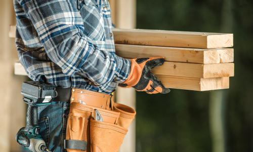 A contractor carrying lumber.