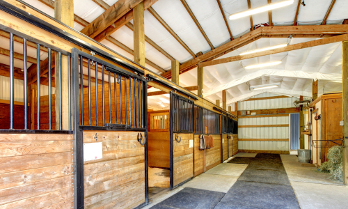 The interior of a pole barn with horse stalls.